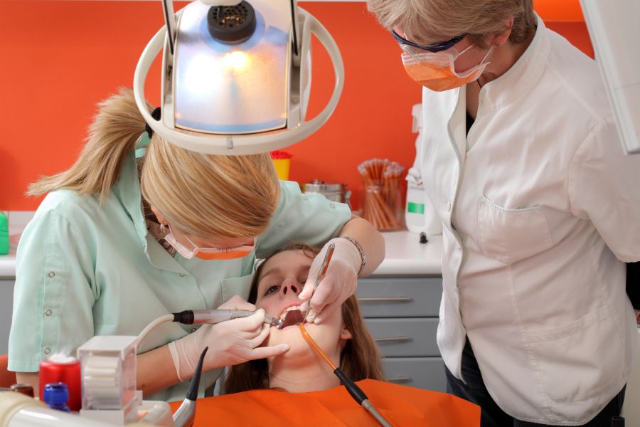 Dentist student drilling  tooth of a young patient with professor looking, real people