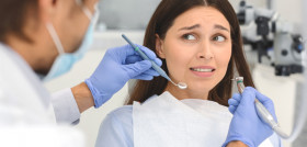 odontofobia_miedo_dentista_Scared woman at dental office, looking panickly at dentist