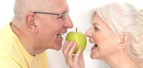 Senior couple with apple, healthy teeth concept