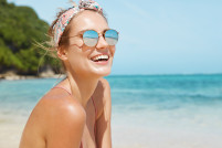 Sonrisa verano mujer bonita con gafas de sol y traje de bano en la playa