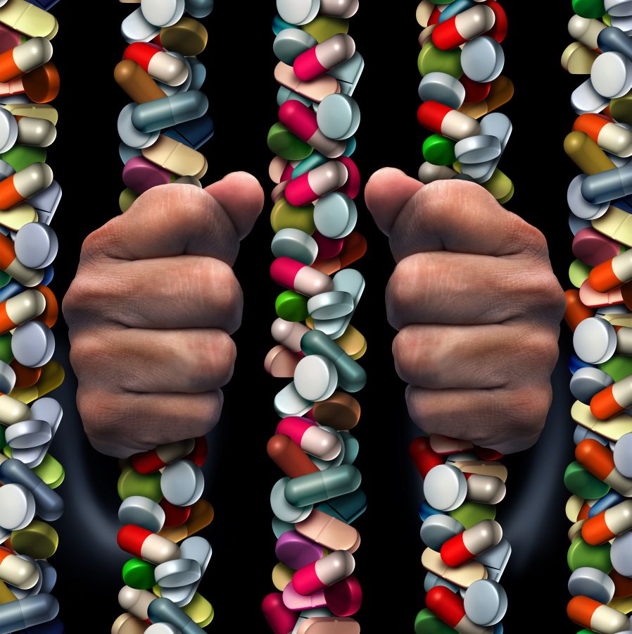 Prescription drug addiction medical concept as a group of medicine capsules and painkiller pills shaped as prison or jail bars as a health care symbol with a medication addict trapped inside.